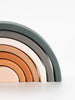 The Handmade Rainbow Stacker - Mojave Desert is a minimalist wooden stacking toy that features six semi-circular arches in earthy tones of green, gray, white, beige, orange, and terracotta. Each piece is handmade with non-toxic paint and arranged in descending size order against a plain white background.