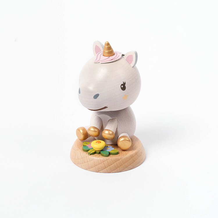 A Wooden Unicorn Bobblehead sitting on a base, with a neutral gray body, golden hooves, and a pink and gold horn, surrounded by small wooden flowers.