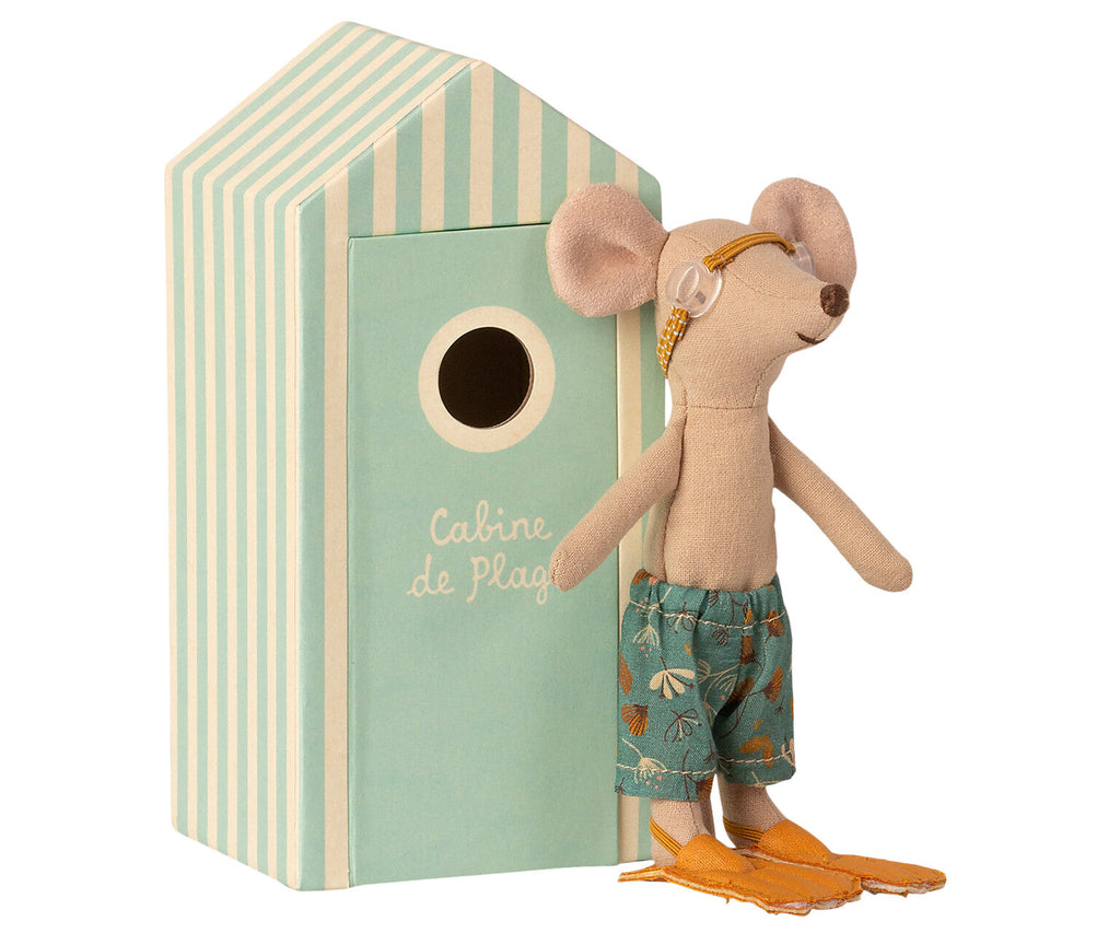 A Maileg Beach Mouse - Big Brother wearing snorkeling goggles, swim trunks with a seashell pattern, and orange flippers. The mouse is standing beside a small green and white striped toy beach house labeled "Cabine de Plage.