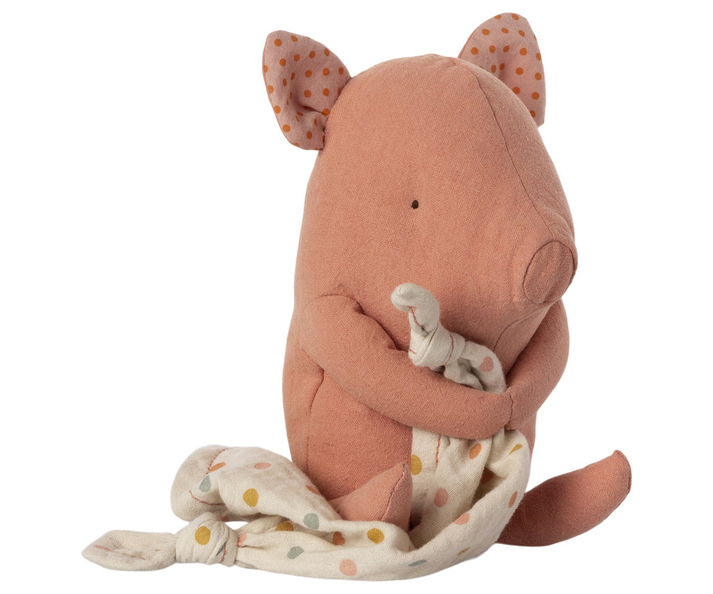 A Maileg Lullaby Friends - Pig (Plays Music) with pink fabric and small black eyes. Its ears are folded with a polka dot pattern on the inside. The piglet, perfect as a baby gift, holds a soft white blanket adorned with multicolored polka dots. This adorable member of the lullaby friends sits upright against a plain white background.