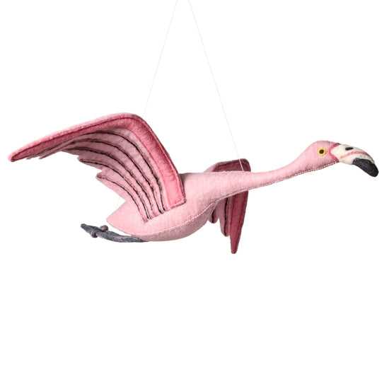 The Hanging Felt Flamingo is a handmade ornament featuring outstretched wings, a black-tipped beak, and yellow eyes. Crafted from organic wool and detailed with darker pink accents using eco-friendly dyes, it creates a whimsical appearance perfect for any decor.