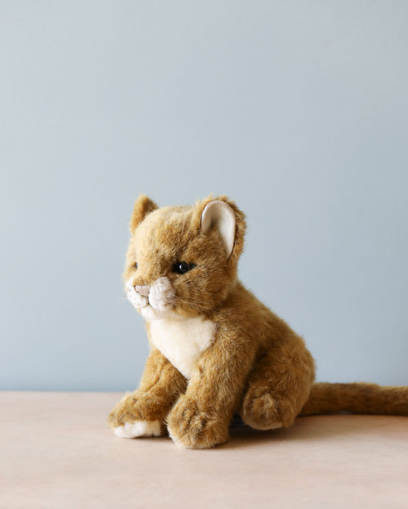 A Lion Cub Stuffed Animal with a lifelike appearance, featuring high-quality plush materials, brown fur, and a white muzzle, sitting against a plain light blue background.