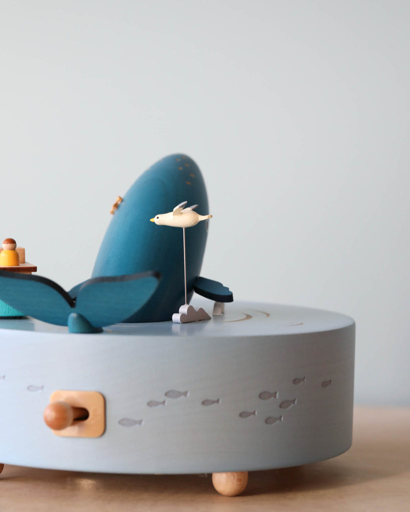 Wooden ocean themed music box with a blue whale in the center and a boat going around it. 