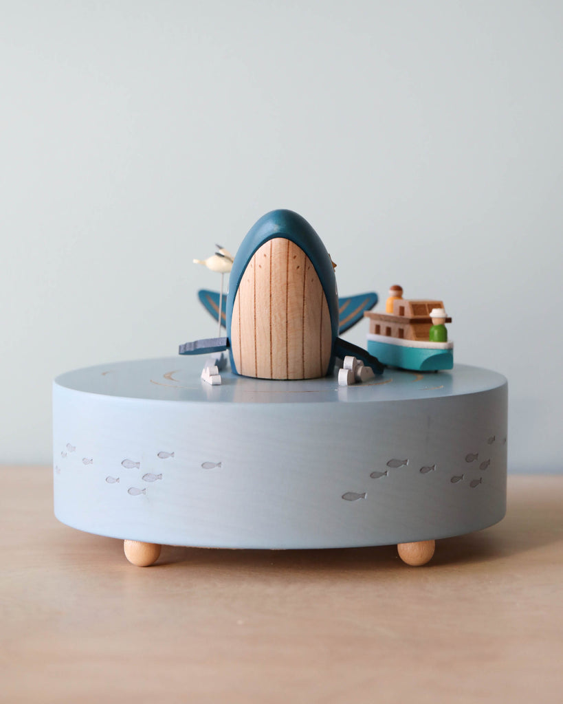 Wooden ocean themed music box with a blue whale in the center and a boat going around it. 