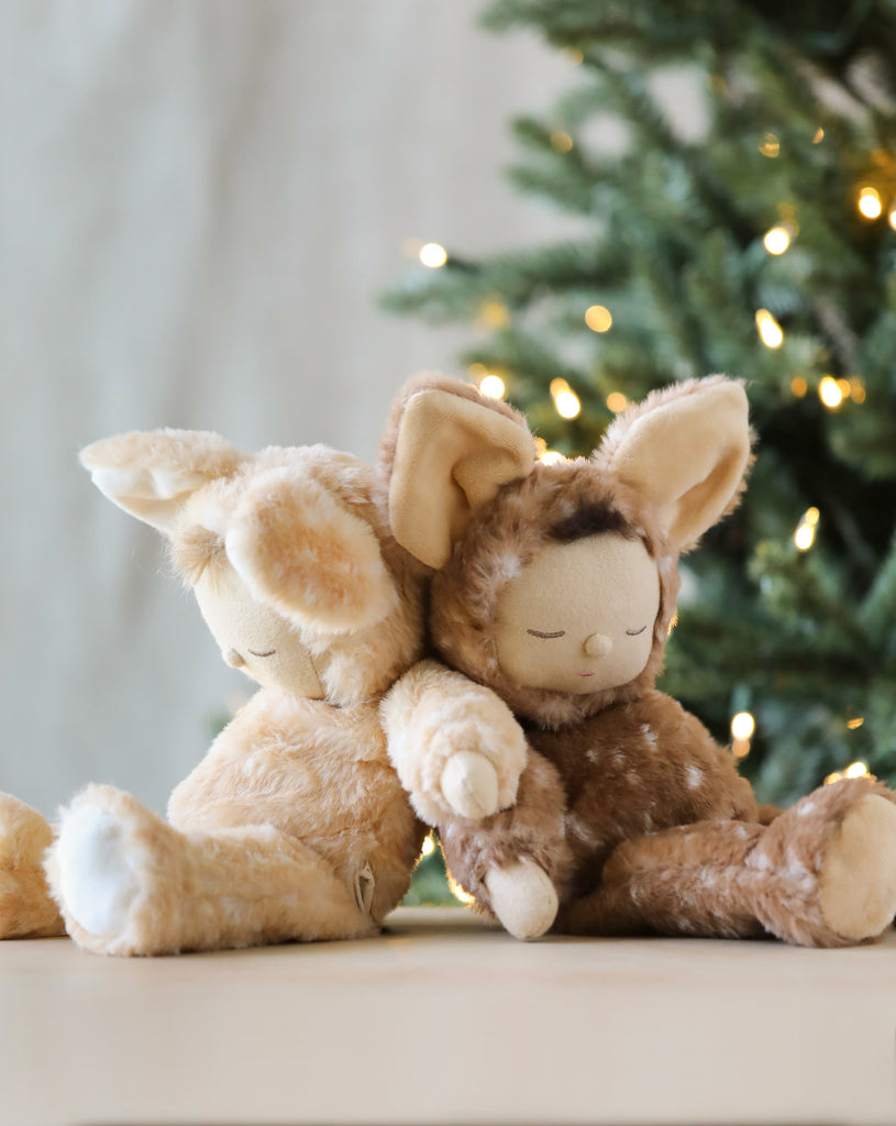 Two stuffed dolls in deer costumes photographed leaning against each other. 