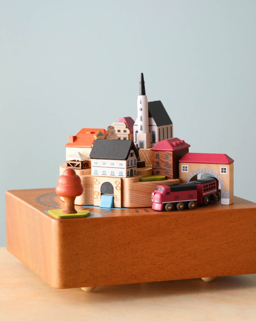 wooden music box with a town in the middle and red train going around it