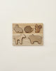 A Handmade Wooden Woodland Puzzle featuring cut-out animal shapes, including a bear, squirrel, pig, snail, and another bear. The light-colored wooden pieces are set against a matching background and treated with beeswax for a smooth finish, all beautifully mounted on a wall.