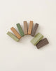 A semicircle arrangement of eight Handmade Wooden Building Blocks in earthy tones such as green, brown, and tan, crafted from linden wood to enhance fine motor skills, is elegantly displayed on a plain white background.