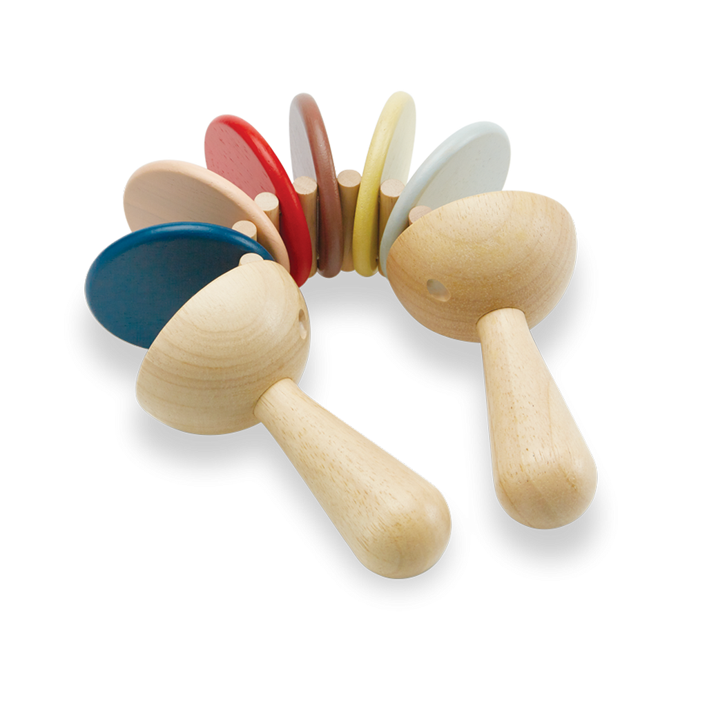 Two sustainably made Clatter Percussion Toys with colorful tops lined up alongside each other against a black and white gradient background.