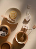 Abstract arrangement of ceramic dishes and a Handmade Wooden Tea Set - Flower with subtle shadows on a textured surface, featuring circular patterns and slices of citrus.