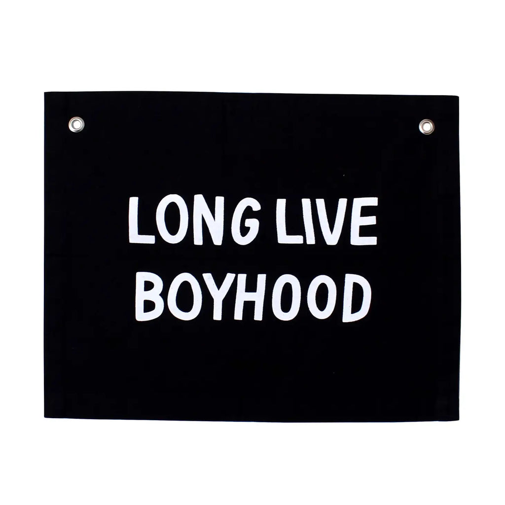 A black canvas Long Live Boyhood Banner with the text "LONG LIVE BOYHOOD" written in bold white letters. Handmade by skilled Kenyan artisans, it features two metal grommets at the top corners for hanging.