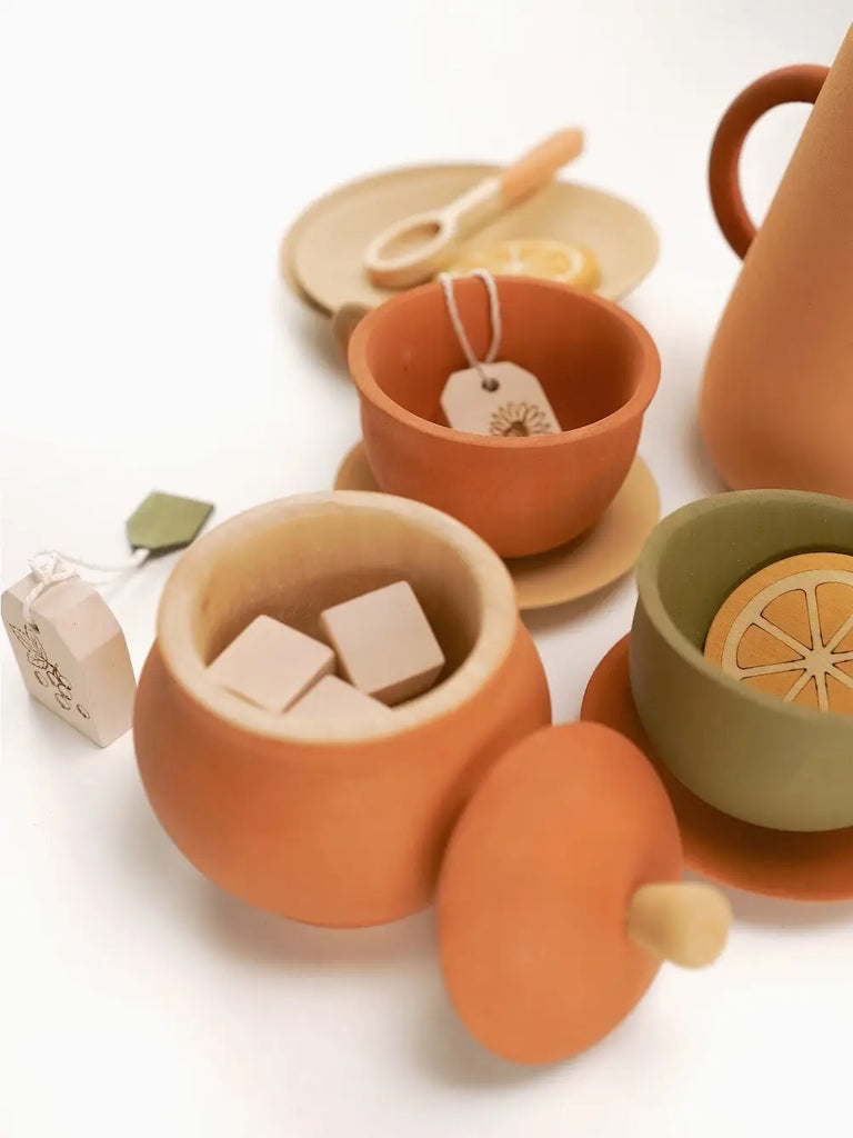 A collection of Handmade Wooden Tea Set - Herbal items including a teapot, cups with lemon slices, and saucers with tea bags on a white background.