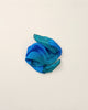 A crumpled turquoise Sarah's Silk Playsilk - Ocean arranged in a loose, imaginative shape on a plain white background.