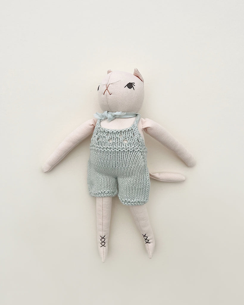 Handmade Polka Dot Club Cat in Hand Knit Overalls with hand embroidered features, lying flat on a light background.