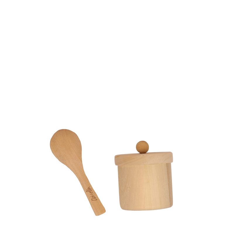 A small wooden doll feeding set with a lid next to a wooden spoon, both set against a plain, dark background.