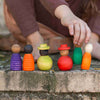 A child's hand arranging colorful Grapat Together in a row on a stone surface. Each figurine has a unique shape and color, ranging from purple to orange.