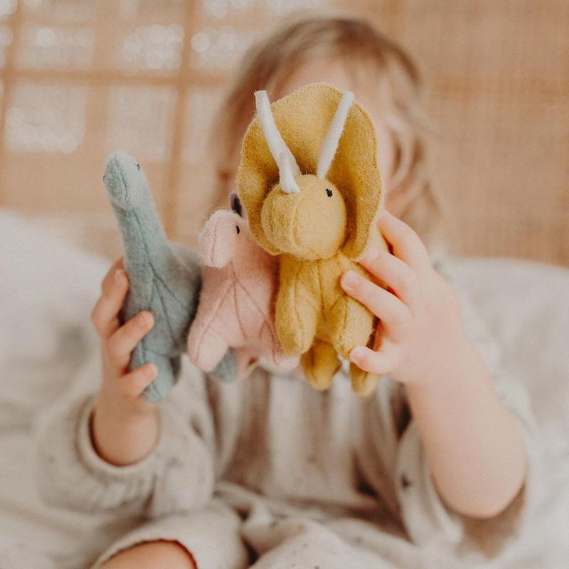 three stuffed dinosaur toys being played by a child.