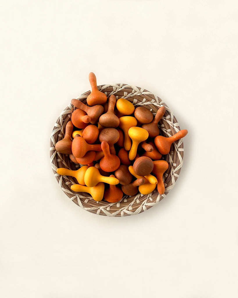 A Grapat Mandala Pumpkins filled with colorful cashew fruits in autumnal hues of orange, yellow, and red, displayed on a light beige background.