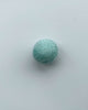 a pastel teal felt ball on a light blue background.