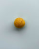 a mustard yellow felt ball on a light blue background.