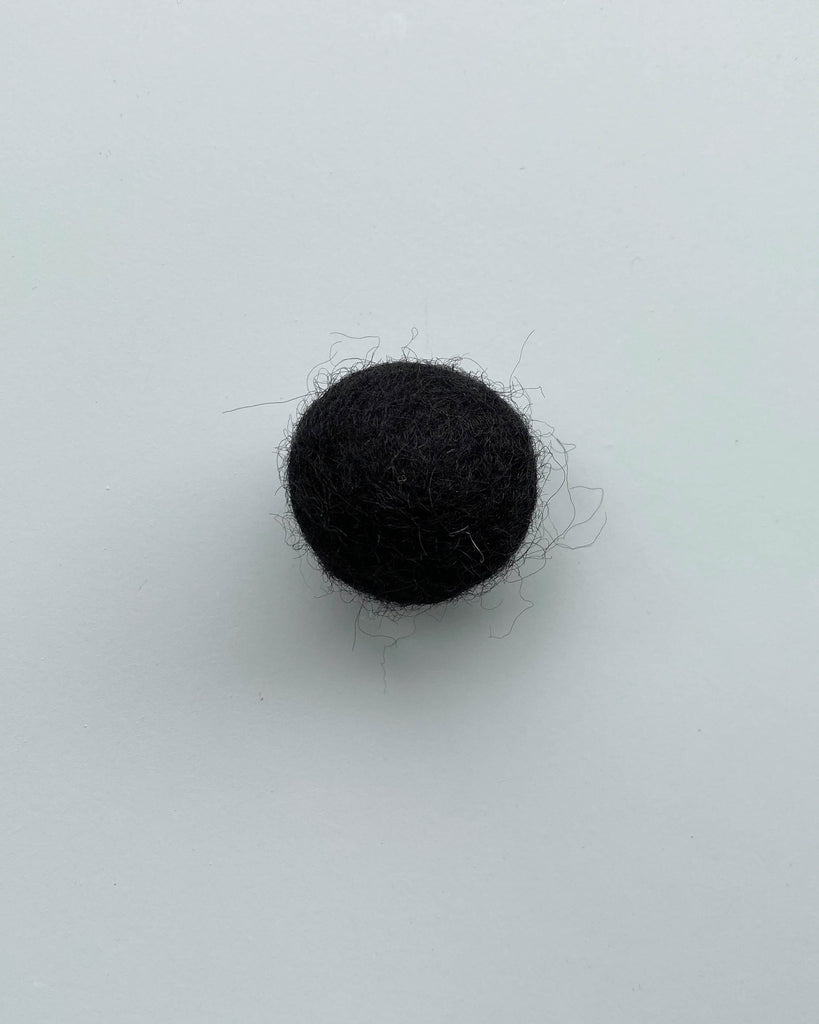 a black felt ball on a light blue background.