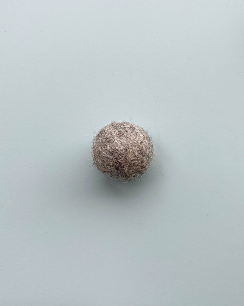 a heather grey felt ball on a light blue background