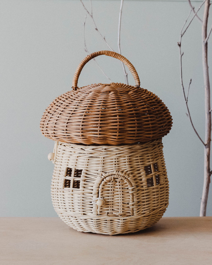 A natural color mushroom rattan basket with tree branches in the background 