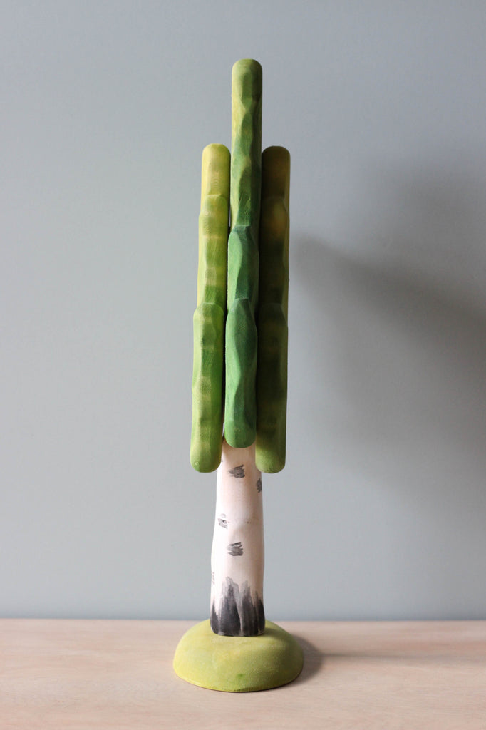 A sculpture of an Extra Large Wooden Tree with a white trunk painted with non-toxic paint, supporting cylindrical green branches against a plain background.