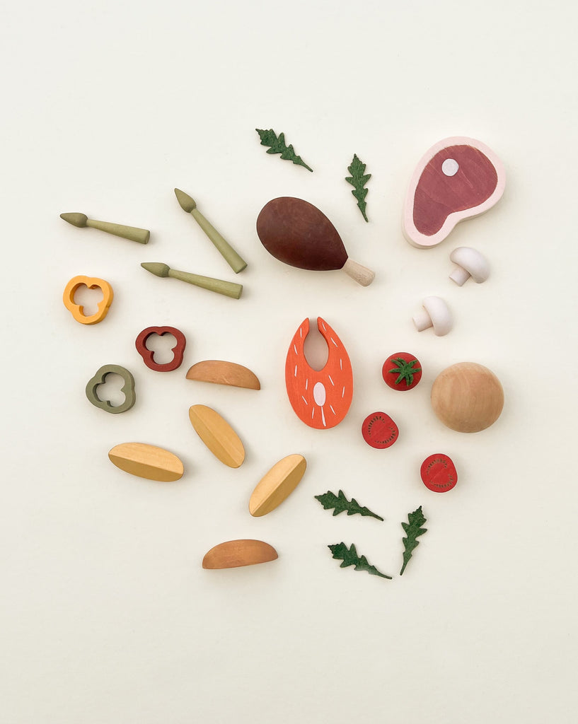 A collection of Sabo Concept Handmade Wooden Dinner Set items including fruits, vegetables, and meat, coated with non-toxic paint, arranged neatly on a light background.