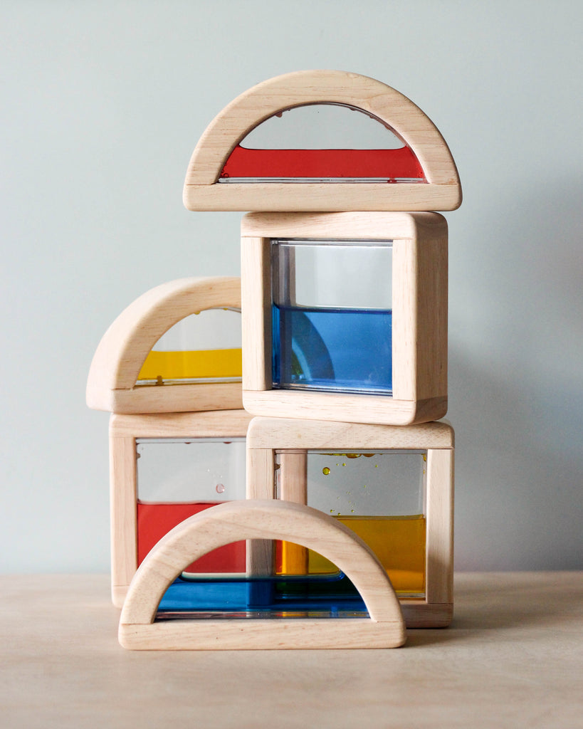 A stack of three Wooden Water Blocks, each containing colorful translucent panels in red, yellow, and blue, arranged on a light gray surface against a neutral background.