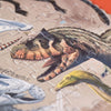 A close-up image of the partially completed Londji Dino Explorer Puzzle (350 pcs) features illustrated dinosaurs, including a large Theropod with brown and green coloring. The intricately detailed pieces fit together against an orange background, making this educational toy both engaging and visually stunning.