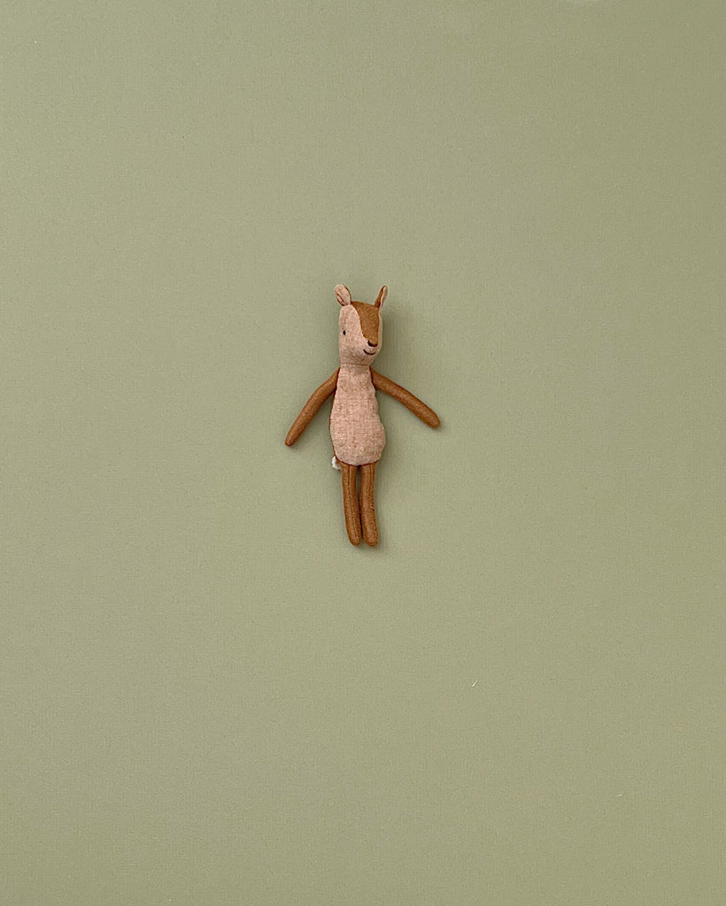 A small deer stuffed animal photographed on a flat background.