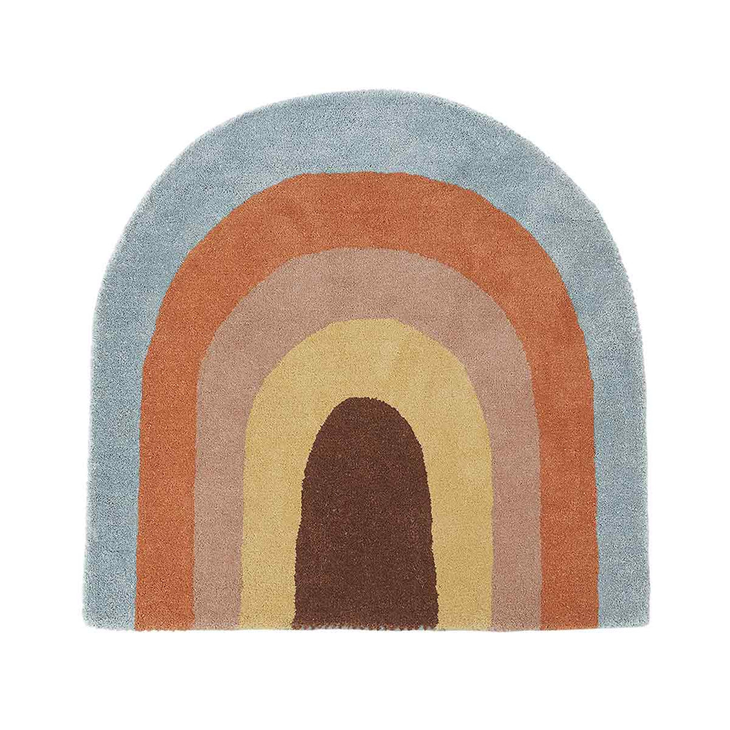 The Oyoy Rainbow Rug from OYOY Living Design is a semi-circular, multicolored piece that showcases concentric arches in various shades including brown, tan, gold, rust, and light blue. The design features the broadest arch in light blue along the outer edge, with progressively darker hues leading to a dark brown center—an ideal addition to any children's room.