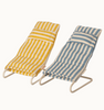 Two Maileg Beach Chairs And/Or Umbrella, reminiscent of striped beach chairs, are displayed side by side. The chair on the left has yellow and white stripes, while the one on the right features blue and white stripes. Both have white metal frames and a headrest, evoking a relaxing day at the beach.