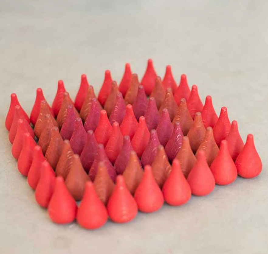 A triangular arrangement of Grapat Mandala Cones Fire made with non-toxic dyes on a light grey surface.