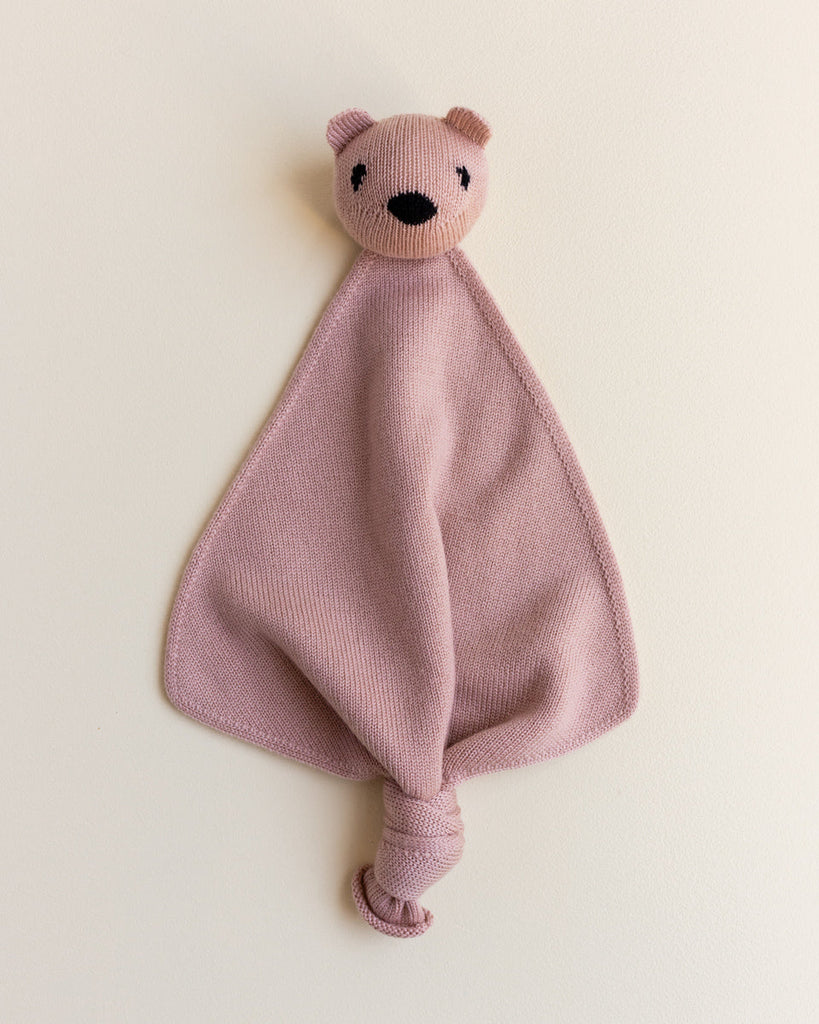 A small merino wool lovey in blush color with a head of a teddy bear at the top.