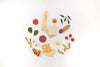 Assorted Sabo Concept handmade wooden play food items including fruits, vegetables, bread, cheese, and meat, neatly arranged on a white background and coated in non-toxic water-based paint.