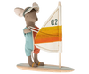 A Maileg Surfer Big Brother Mouse dressed in a sun visor and a sleeveless jumpsuit stands on a wooden surfboard, holding an upright sail with "Q2" written on it. The sail is white with yellow and orange stripes, perfect for surfer mice.