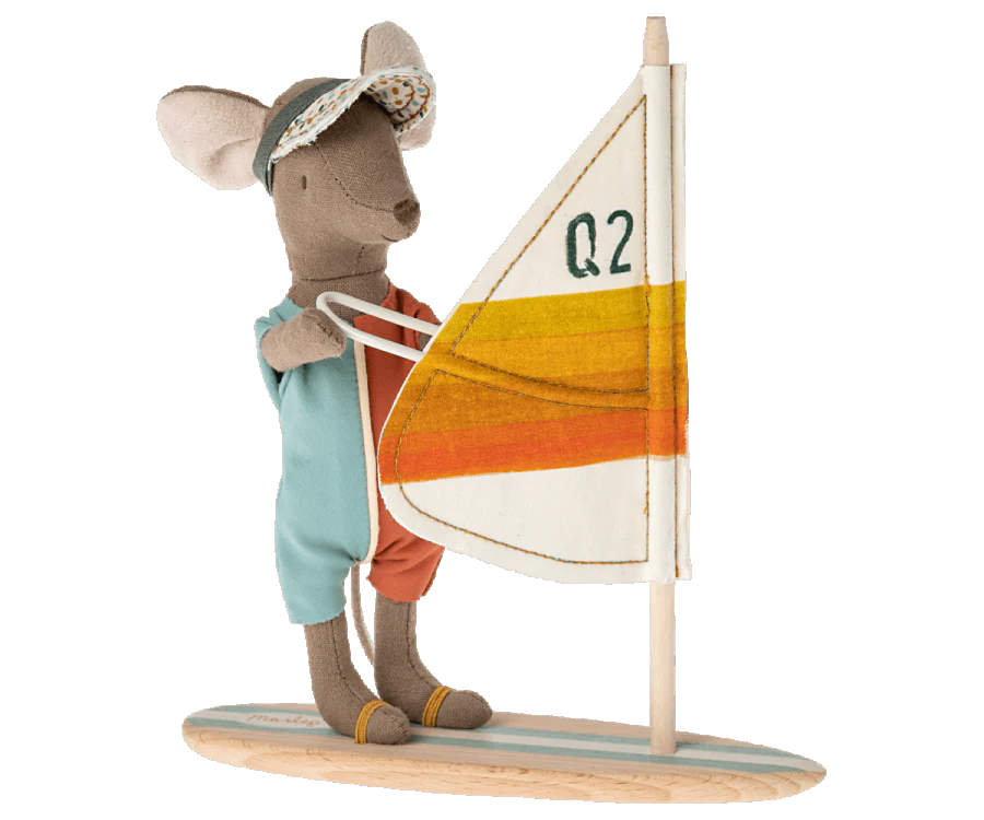 A Maileg Surfer Big Brother Mouse dressed in a sun visor and a sleeveless jumpsuit stands on a wooden surfboard, holding an upright sail with "Q2" written on it. The sail is white with yellow and orange stripes, perfect for surfer mice.