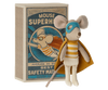 A Maileg | Superhero Mouse, Little Brother plush toy mouse dressed as a superhero with a cape and eye mask, standing beside a vintage book titled "Mouse Superhero." The toy and book display a charming, whimsical