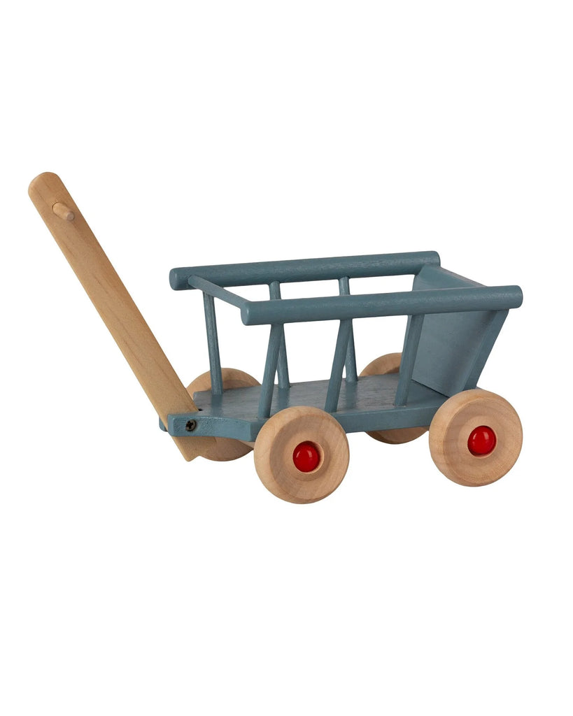 A Maileg Wagon painted in blue with a natural wood handle and four red wheels, isolated on a white background.