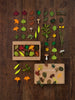 An assortment of colorful paper Woodland Leaves and small mushrooms arranged neatly on a wooden surface, alongside a box labeled "wooden leaves.