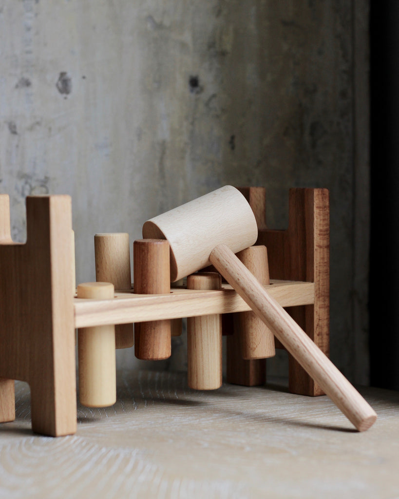 A wooden pounding toy with a wooden hammer on top.