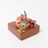 wooden music box with a town in the middle and red train going around it