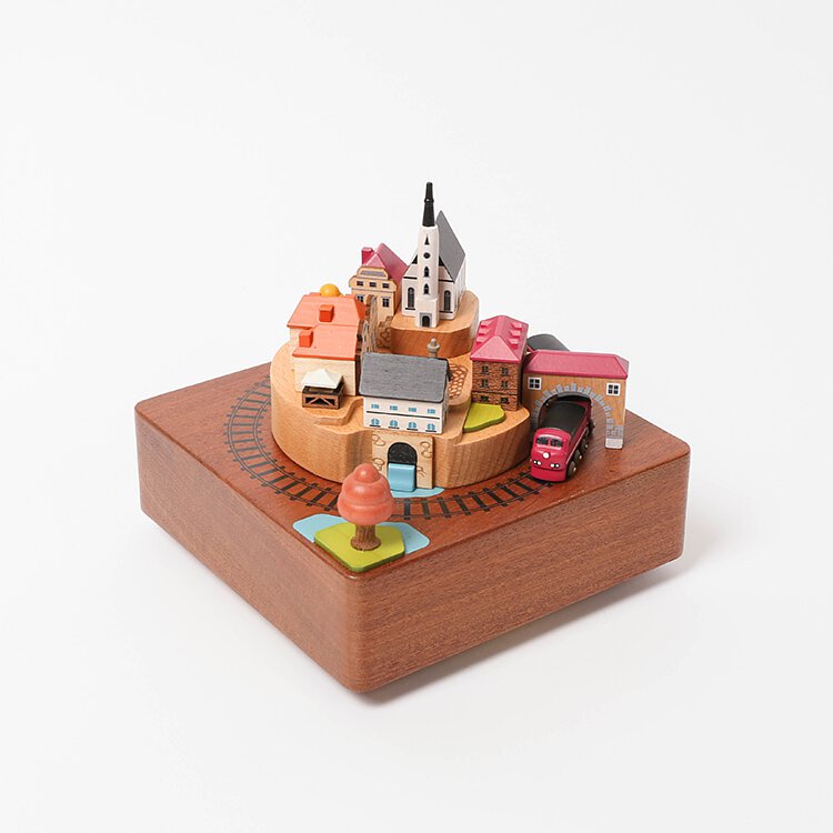 wooden music box with a town in the middle and red train going around it